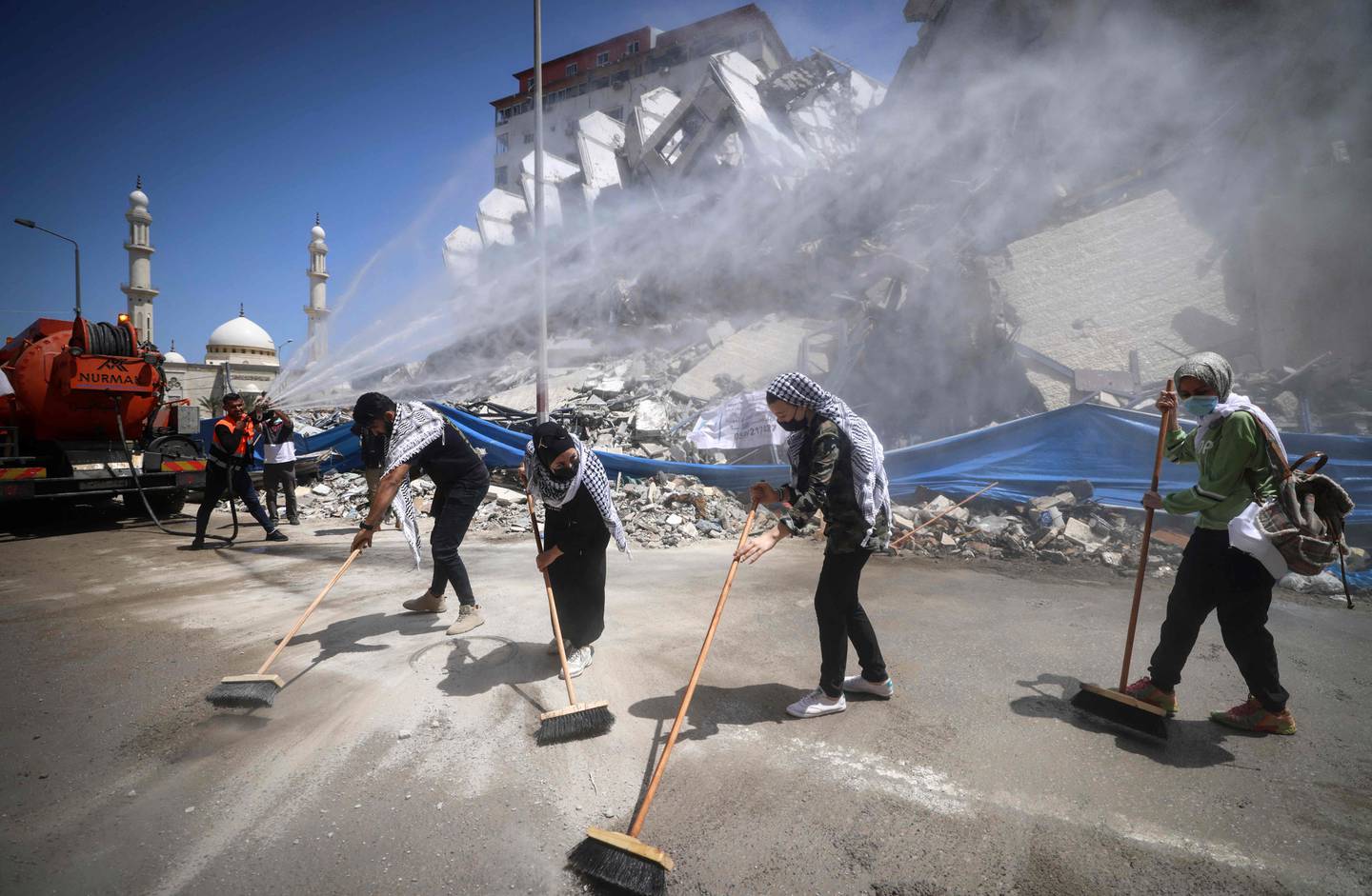 Palestinske frivillige koster gatene etter israelske bombeangrep i Gaza tirsdag. USAs utenriksminister Antony Blinken lover å bidra til å gjenoppbyggingen.
