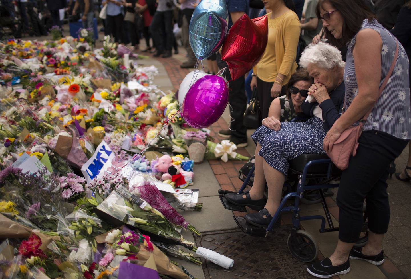 FILE - In this May 24, 2017 file photo women cry after placing flowers in a square in central Manchester, Britain, after the suicide attack at an Ariana Grande concert that left more than 20 people dead and many more injured, as it ended on Monday night at the Manchester Arena.