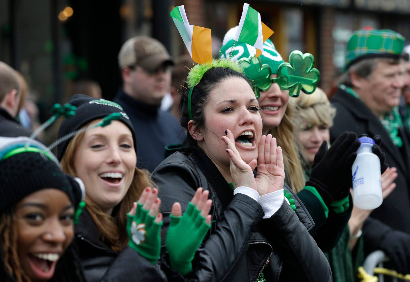 Spectators cheer during the St. Patrick's Day parade, Sunday, March 15, 2015, in Boston's South Boston neighborhood. Sunday's parade through the traditionally Irish-American enclave was shorter than years past: So much snow remains piled on sidewalks after the brutal winter that the city has had to cut the route in half. (AP Photo/Steven Senne)