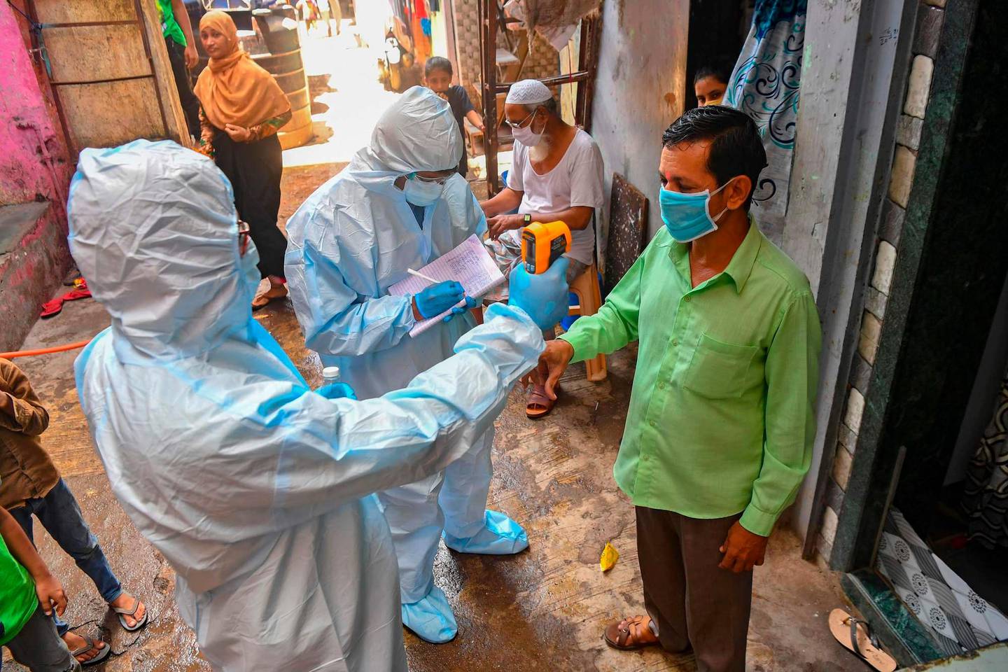 Medical staff wearing Personal Protective Equipment (PPE) gear conduct a door-to-door medical screening inside Dharavi slums to fight against the spread of the COVID-19 coronavirus, in Mumbai on June 24, 2020. - The epidemic has badly hit India's densely populated major cities -- including the national capital New Delhi and the financial hub Mumbai -- with reports of hospitals being overwhelmed and patients struggling to find beds. (Photo by INDRANIL MUKHERJEE / AFP)