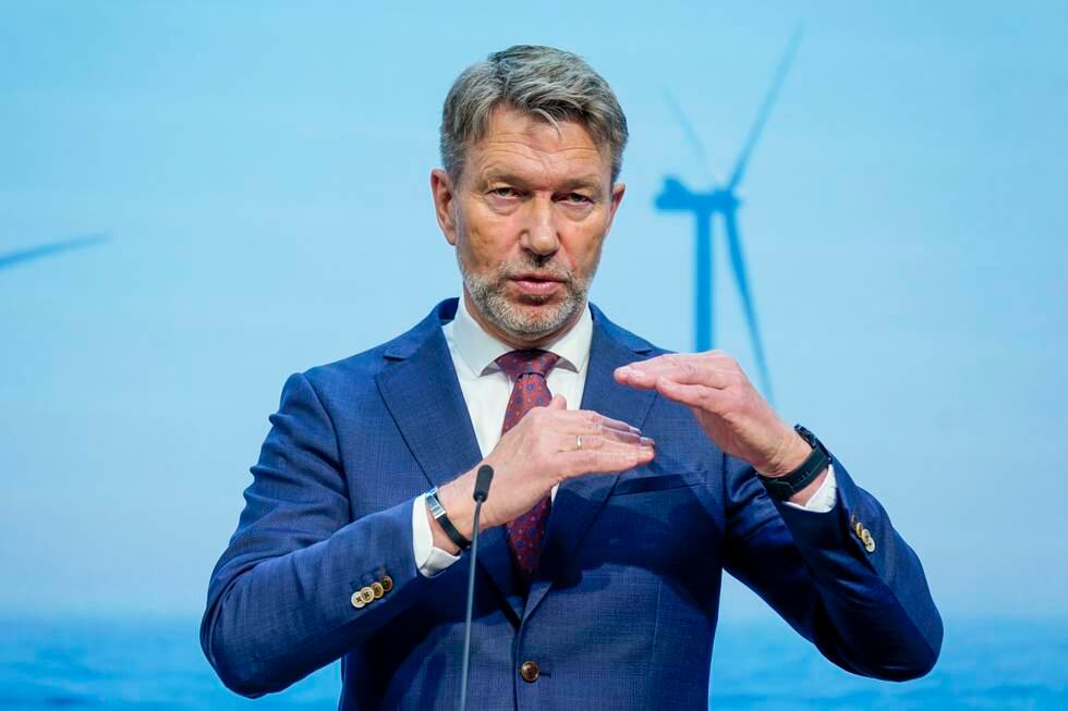Bildet er av olje- og energiminister Terje Aasland. Han holder hendene opp foran seg, den ene litt høyere enn den andre. De er vannrett. I bakgrunnen er det en skjerm der det er bilde av en vindmølle. Foto: Lise Åserud / NTB