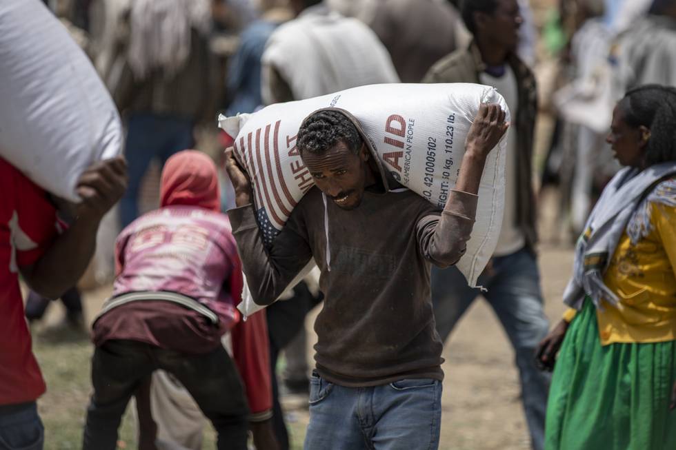 En mann i Agula i Tigray-regionen i Etiopia bærer på en sekk hvete han har fått utdelt. Etiopia er blant landene der mange er rammet av sult. Foto: Ben Curtis / AP / NTB