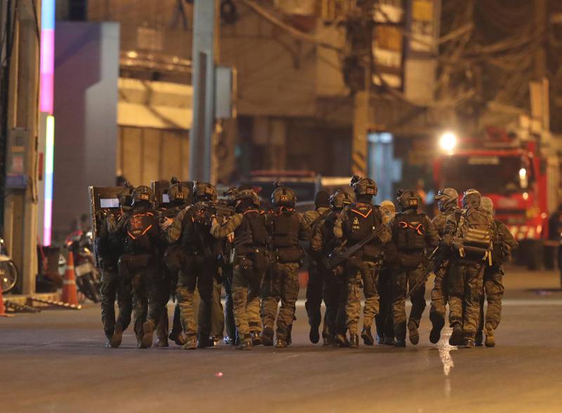 A group of armed commando soldiers walk close together outside Terminal 21 Korat mall, in Nakhon Ratchasima, Thailand on Sunday, Feb. 9, 2020. A soldier who holed up in a popular shopping mall in northeastern Thailand shot multiple people on Saturday, killing at least 20 and injuring 31 others, officials said. (AP Photo/Sakchai Lalitkanjanakul)
