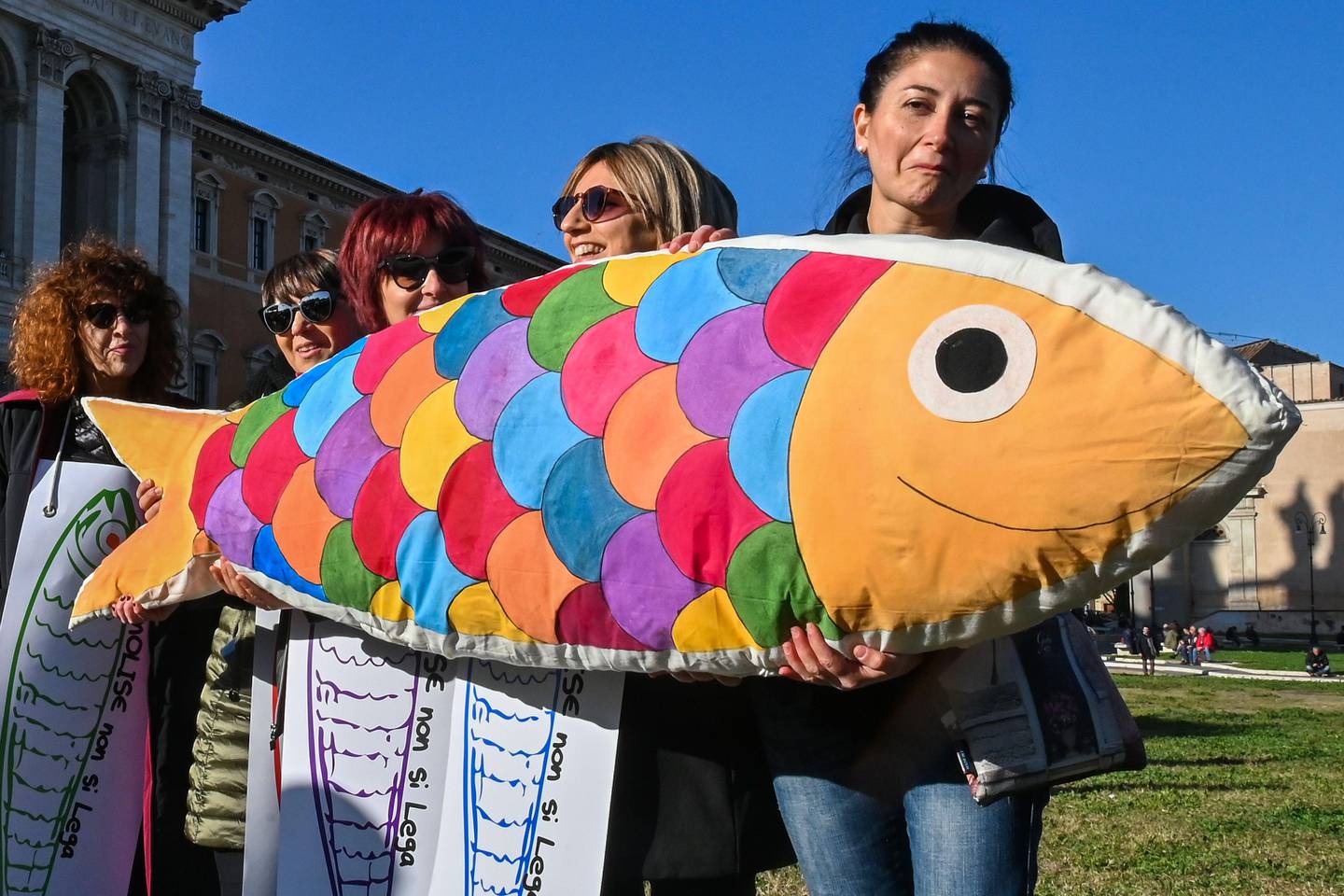 Woman holding several drawings of sardines and a giant sardine-shaped stuffed cushion take part in a demonstration of the "Sardine Movement", formed to oppose the far-right League party, on December 14, 2019 by the Basilica San Giovanni in Laterano in Rome. - Italy's youth-driven "Sardine Movement", formed to oppose the far-right League party, was launched by four little-known youths saying the anti-immigration League party led by Matteo Salvini represents hate and exclusion. The sardine has become a symbol of protest against Salvini, a former interior minister. (Photo by ANDREAS SOLARO / AFP)