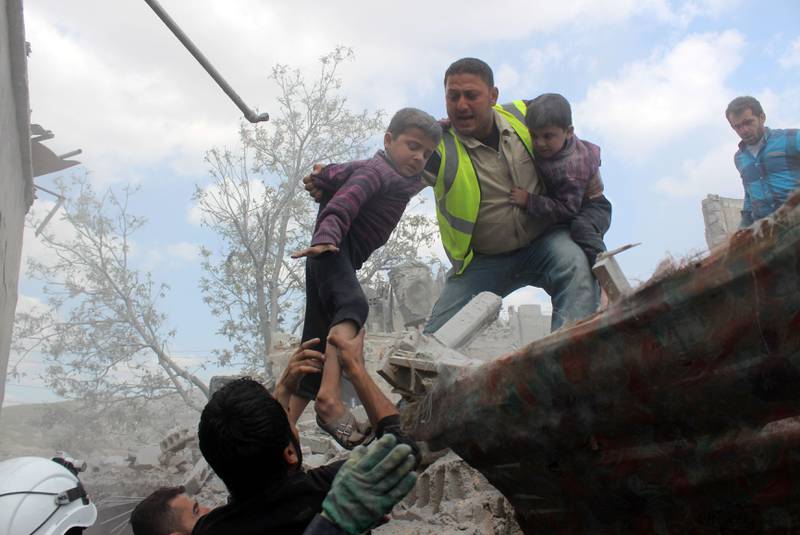En hjelpearbeider redder et barn ut av et bombet hus i byen Aleppo i mai. Den syriske borgerkrigen har gått svært hardt ut over sivilbefolkningen. FOTO: KARAM AL-MASRI /NTB SCANPIX