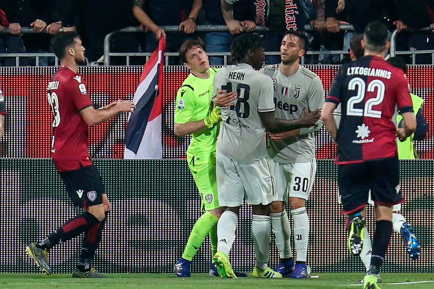 Juventus' Moise Kean, third from left, is restrained by Cagliari goalie Alessio Cragno, 2nd left, and his teammate Rodrigo Bentancur as he celebrates in front of Cagliari fans after scoring his side's second goal during a Serie A soccer match between Cagliari and Juventus at the Sardegna Arena Stadium in Cagliari, Italy, Tuesday, April 2, 2019. Cagliari fans shouted racist chants at Kean after the 19-year-old scored in the 85th minute, the chants were so bad that Cagliari captain Luca Ceppitelli rushed in to protect the youngster and ask the fans to stop. (Fabio Murru/ANSA via AP)