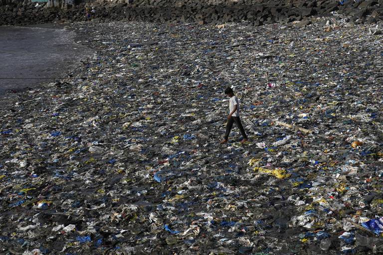 En gutt går blant plastforurensing på Badhwar Park-stranden ved Det arabiske hav i Mumbai, India.