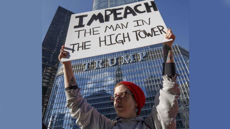 Sarah Scott demonstrerer utenfor Trump Tower i Chicago tidligere i januar, med plakaten «Riksrett for mannen i det høye tårnet». Trumps første uker i presidentjobben har møtt massive protester og krav om at han må bli stilt for retten.