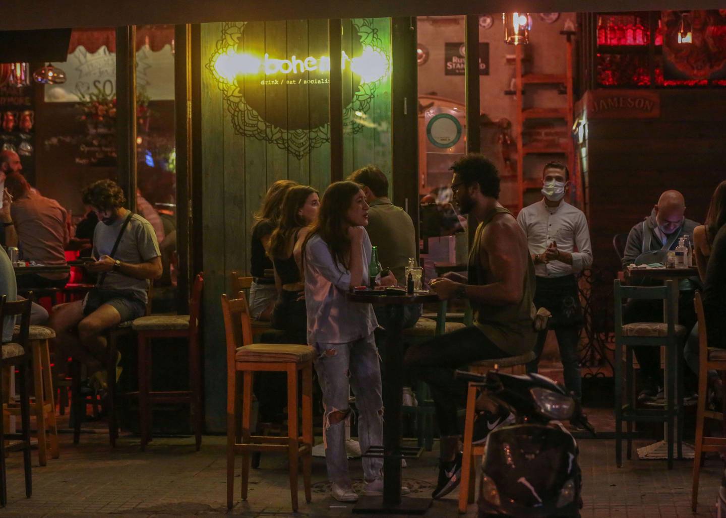 People gather at the terrasse of a bar in the trendy neighborhood of Gemmayzeh in the Lebanese capital Beirut on June 1, 2020, as the country is set to gradually open up, after weeks of lockdown to stem the spread of the novel coronavirus. - The worst of the coronavirus pandemic has passed but declaring victory against the disease would be premature, Lebanon's health minister said, a day after the government announced easing restrictions in the upcoming week, including a curfew which is pushed back from 7:00 pm to midnight. (Photo by PATRICK BAZ / AFP)