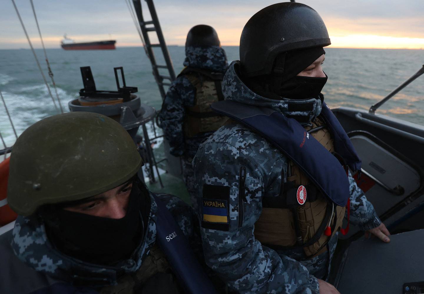 Servicemen of the Maritime Guard of the State Border Service of Ukraine look towards a cargo ship during an inspection for prohibited items and substances in the territorial waters of Ukraine on 18 December 2023, amid the Russian invasion in Ukraine. This patrol is part of Kyiv's strategy aimed at keeping the Russian military fleet away from the Ukrainian coast, with the key mission of securing the corridor set up since August between Ukrainian ports in the Odessa region and the Bosphorus Strait, after Moscow slammed the door on an international grain agreement. (Photo by Anatolii Stepanov / AFP)