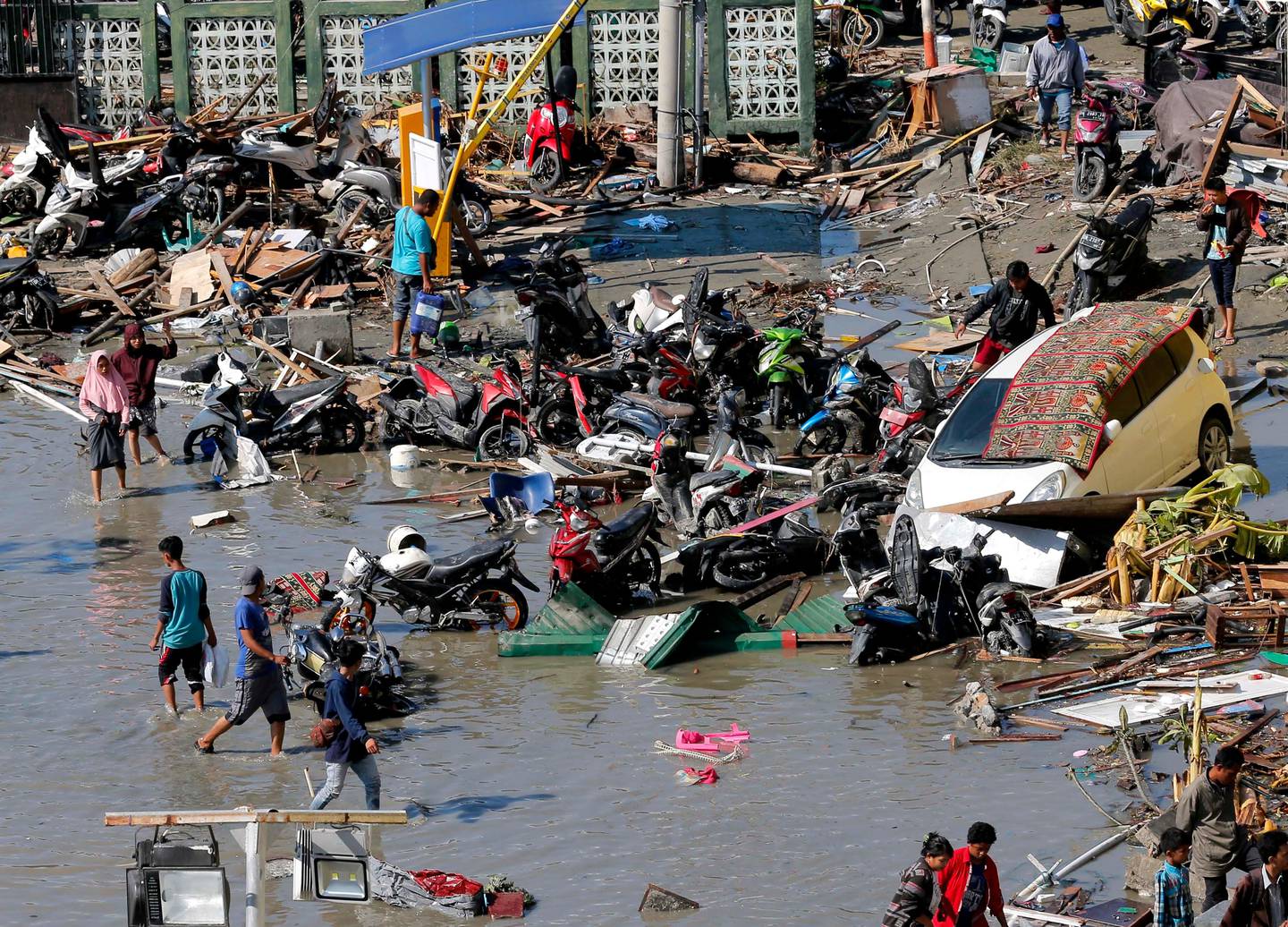 People survey damage outside the shopping mall following earthquakes and tsunami in Palu, Central Sulawesi, Indonesia, Sunday, Sept. 30, 2018. Rescuers try to reach trapped victims in collapsed buildings after hundreds of people are confirmed dead in a tsunami that hit two central Indonesian cities, sweeping away buildings with massive waves. (AP Photo/Tatan Syuflana)