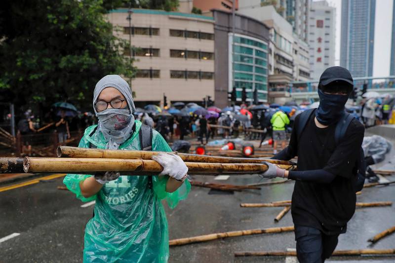 Demonstrators carry bamboos sticks to block a road during a protest in Hong Kong, Sunday, Aug. 25, 2019. Umbrella-carrying protesters took to the streets in the rain Sunday in Hong Kong's latest pro-democracy demonstration, one day after the return of clashes with police who used tear gas to disperse them. (AP Photo/Kin Cheung)
