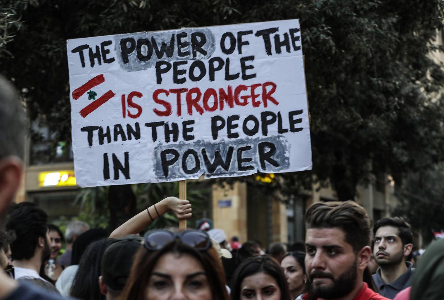 Lebanese demonstrators carry a placard as they take part in a rally in the capital Beirut's downtown district on October 20, 2019. - Thousands continued to rally despite calls for calm from politicians and dozens of arrests. The demonstrators are demanding a sweeping overhaul of Lebanon's political system, citing grievances ranging from austerity measures to poor infrastructure. (Photo by Anwar AMRO / AFP)