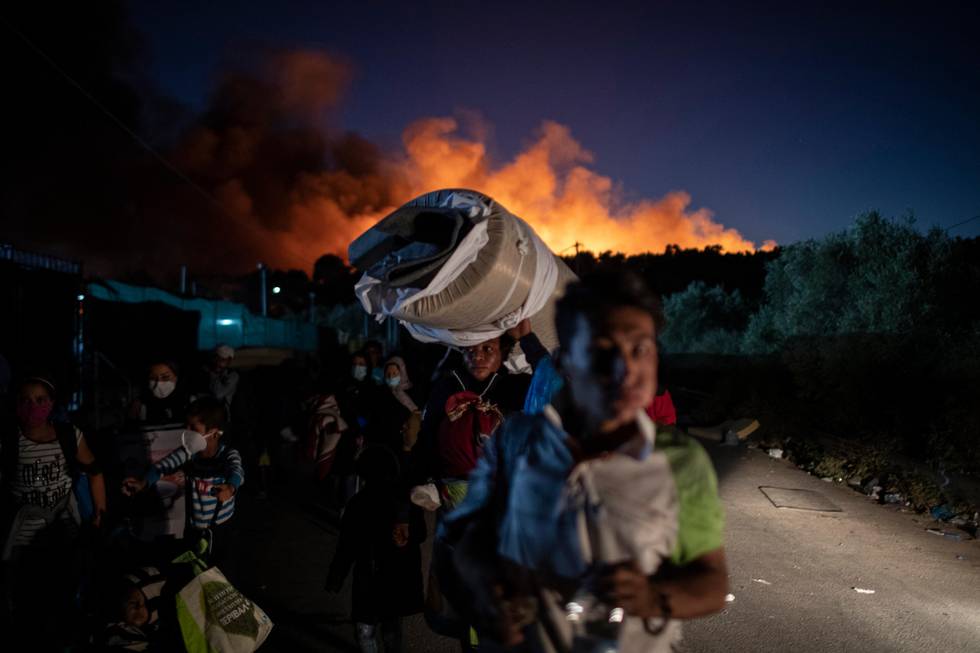 FILE - In this Wednesday, Sept. 9, 2020 file photo, migrants flee from the Moria refugee camp during a second fire, on the northeastern Aegean island of Lesbos, Greece. A Washington-based Syrian rights group filed on Thursday, Jan. 28, 2021 a case with the International Criminal Court calling for an investigation into alleged crimes against humanity by Greece for its treatment of refugees at its borders and in sprawling camps. (AP Photo/Petros Giannakouris, File)
