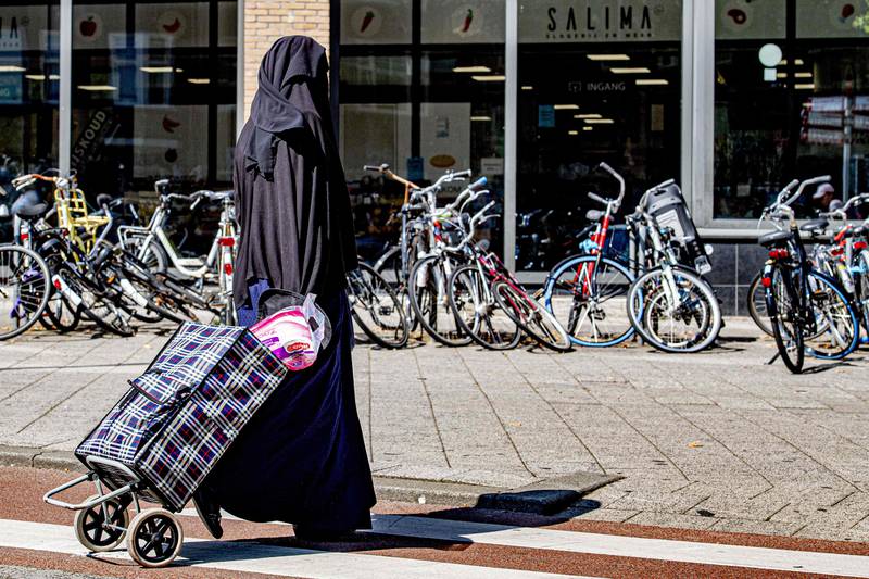 A woman wearing a Niqab Islamic dress, pulls a shopping trolley along a street in Rotterdam on July 29, 2019. - The Netherlands banned the wearing of a face-covering veil, such as a burqa or niqab, in public buildings and on transport from on August 1, 2019, as a contentious law on the garment worn by some Muslim women came into force. Between 200 and 400 women are estimated to wear a burqa or niqab in the country of 17 million people. (Photo by ROBIN UTRECHT / ANP / AFP) / Netherlands OUT