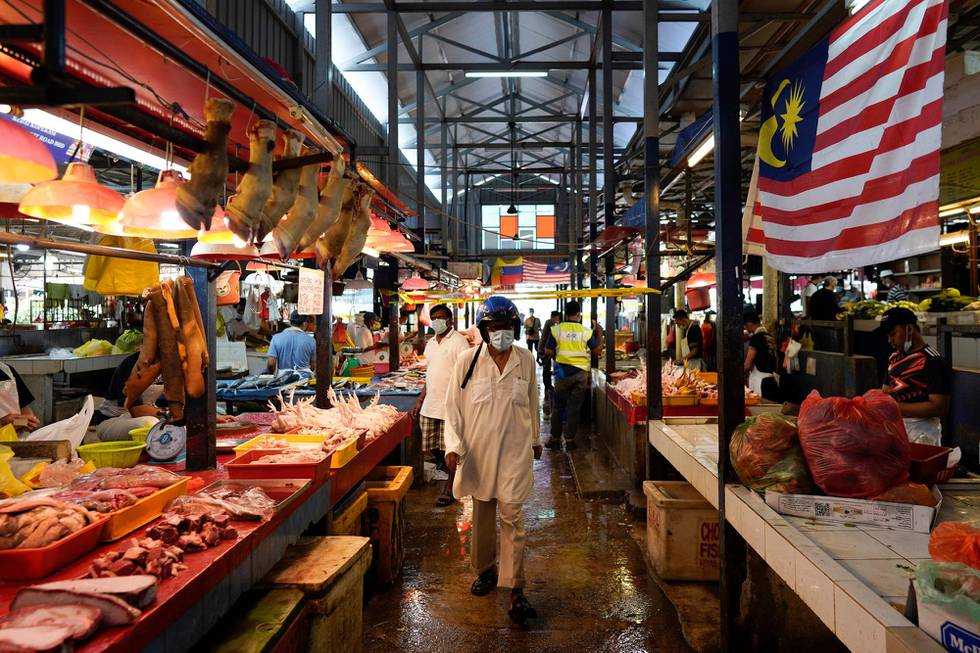 A man wearing a face mask to help curb the spread of the coronavirus shops at a wet market in downtown Kuala Lumpur, Malaysia, Friday, April 24, 2020. Malaysia, along with neighboring Singapore and Brunei, has banned popular Ramadan bazaars where food, drinks and clothing are sold in congested open-air markets or road-side stalls. The bazaars are a source of key income for many small traders, some who have shifted their businesses online. (AP Photo/Vincent Thian)