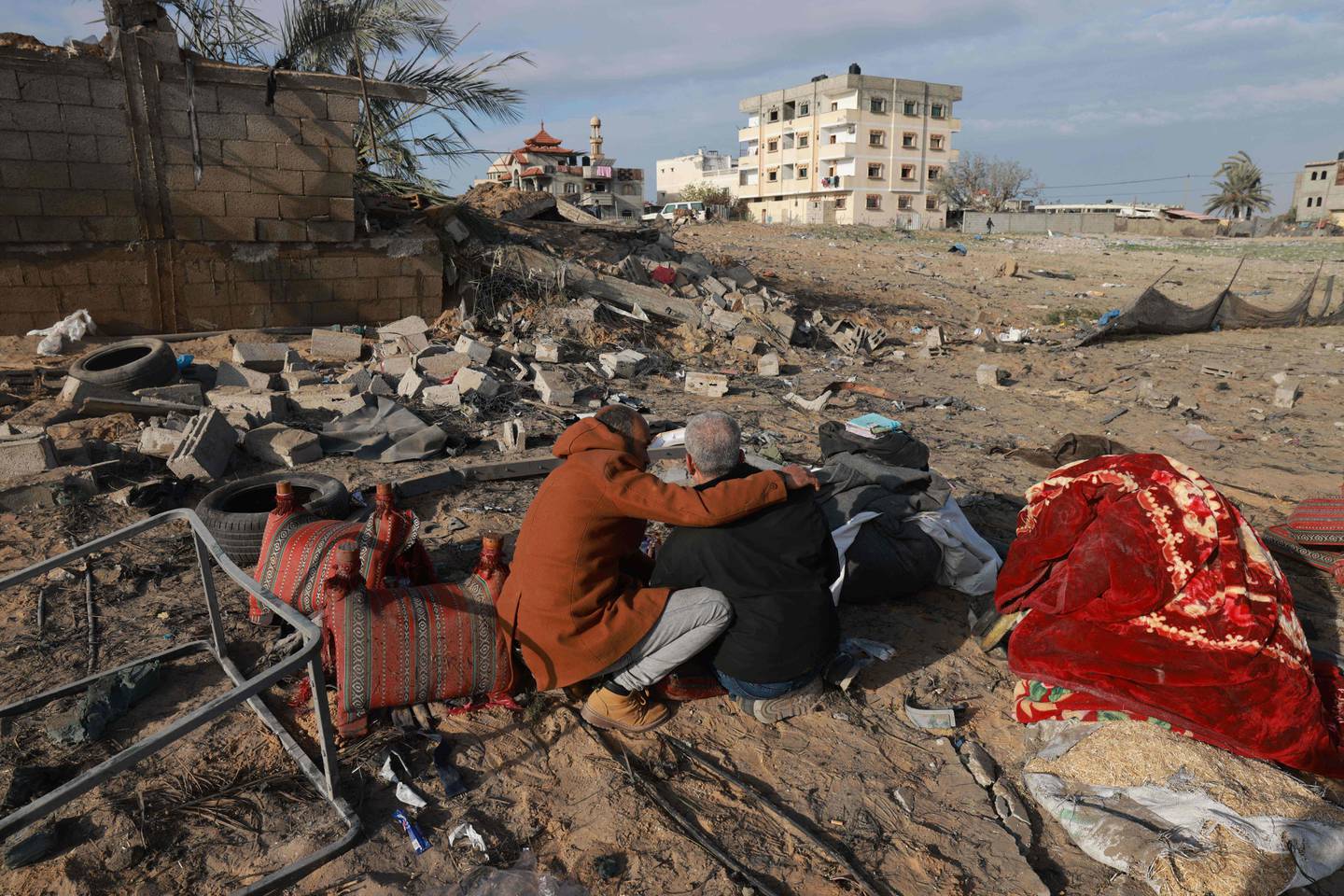 A Palestinian man comforts another as they inspect the destruction in Rafah on February 18, 2024, following overnight Israeli air strikes on the southern Gaza Strip border city amid ongoing battles between Israel and the Palestinian Hamas movement. Prospects for an Israel-Hamas ceasefire dimmed on February 18 after the United States signalled it would veto the latest push for a UN Security Council resolution and mediator Qatar acknowledged that truce talks on the other diplomatic front have hit an impasse. (Photo by MOHAMMED ABED / AFP)
