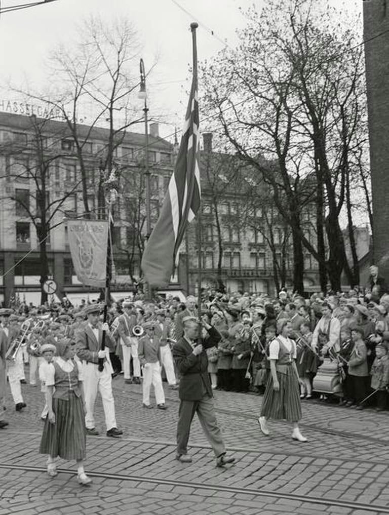 Barnetoget passerer Stortorget 17. mai 1955. Ettervirknngene av militærets brutale framferd under Torgslaget i 1829 la den symbolske grunnen for 17. mai-feiringen som gradvis vokste fram i årene etterpå.
