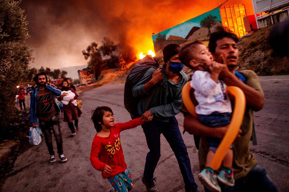 (FILES) In this file photo taken on September 9, 2020 a family of migrants leave the Moria camp after a fire broke out, on the island of Lesbos leaving over 12,000 men fleeing the squalid camp. - The failure of the European Union's migration policy could not have been laid out more starkly -- an already miserable camp burned and thousands of refugees homeless. On September 23, 2020, two weeks after the destruction of the Moria camp on the Greek Island of Lesbos, Brussels will launch its latest proposal for EU asylum policy. (Photo by ANGELOS TZORTZINIS / AFP)