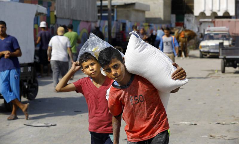 Hjelpen fra UNRWA er nødvendig for mange palestinere. Her bærer palestinske barn i Gaza sekker med mat fra UNRWA.