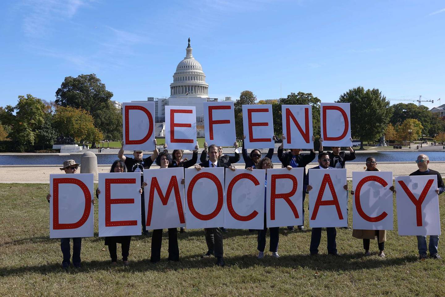Aktivister holder opp plakater som sier «forsvar demokratiet» i en demonstrasjon foran kongressbygningene i oktober i år.