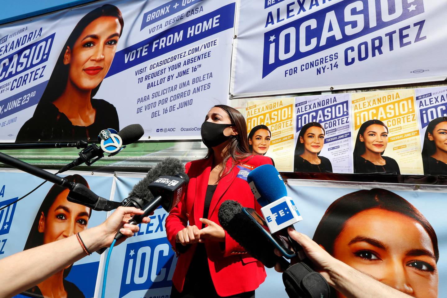 U.S. Rep. Alexandria Ocasio-Cortez, D, New York, center, speaks to members of the media while standing beside a truck plastered with campaign posters after greeting voters in Astoria, Queens, Tuesday, June 23, 2020, on primary election day in New York. (AP Photo/Kathy Willens)
