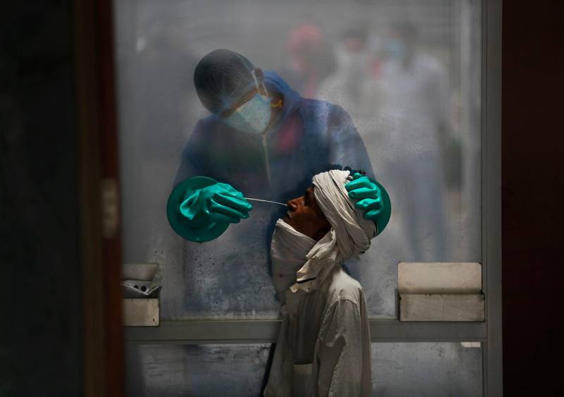 A health worker takes a nasal swab of a person for a COVID-19 test at a hospital in New Delhi, India, on July 6, 2020. (AP Photo/Manish Swarup)