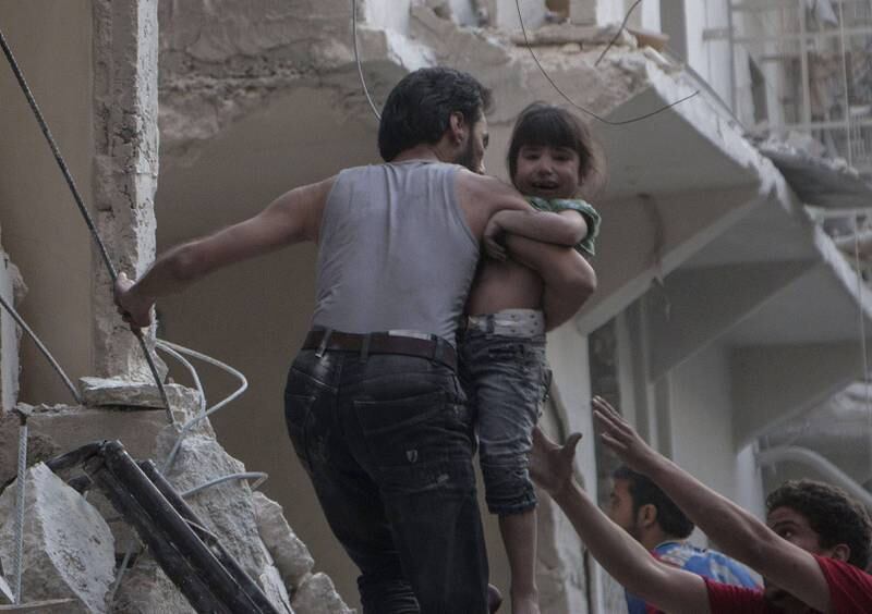 Ei jente løftes ut av en bygning som er truffet av en tønnebombe i den nordligste delen av Aleppo. FOTO: NTB SCANPIX