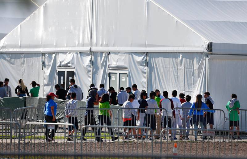 FILE- In this Feb. 19, 2019 file photo, children line up to enter a tent at the Homestead Temporary Shelter for Unaccompanied Children in Homestead, Fla. The company that runs the center is Comprehensive Health Services, which is part of Virginia-based Caliburn International Corporation. Three Democratic lawmakers are requesting a government watchdog agency investigate how a private company tied to former White House Chief of Staff John Kelly secured a no-bid contract to hold migrant children. (AP Photo/Wilfredo Lee, File)