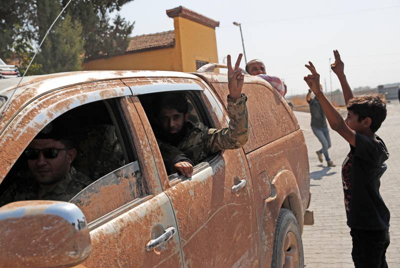 Members of Turkey-backed Syrian National Army (former FSA) flash the V-sign as they drive back to Turkey after they went in for some time on inspection according to the Turkish police entourage in the same area at the border between Turkey and Syria, in Akcakale, Sanliurfa province, southeastern Turkey, Wednesday, Oct. 9, 2019. Turkish President Recep Tayyip Erdogan has long threatened to send troops into northeastern Syria to clear the border region of Syrian Kurdish fighters whom Turkey considers a serious security threat. (AP Photo/Lefteris Pitarakis)