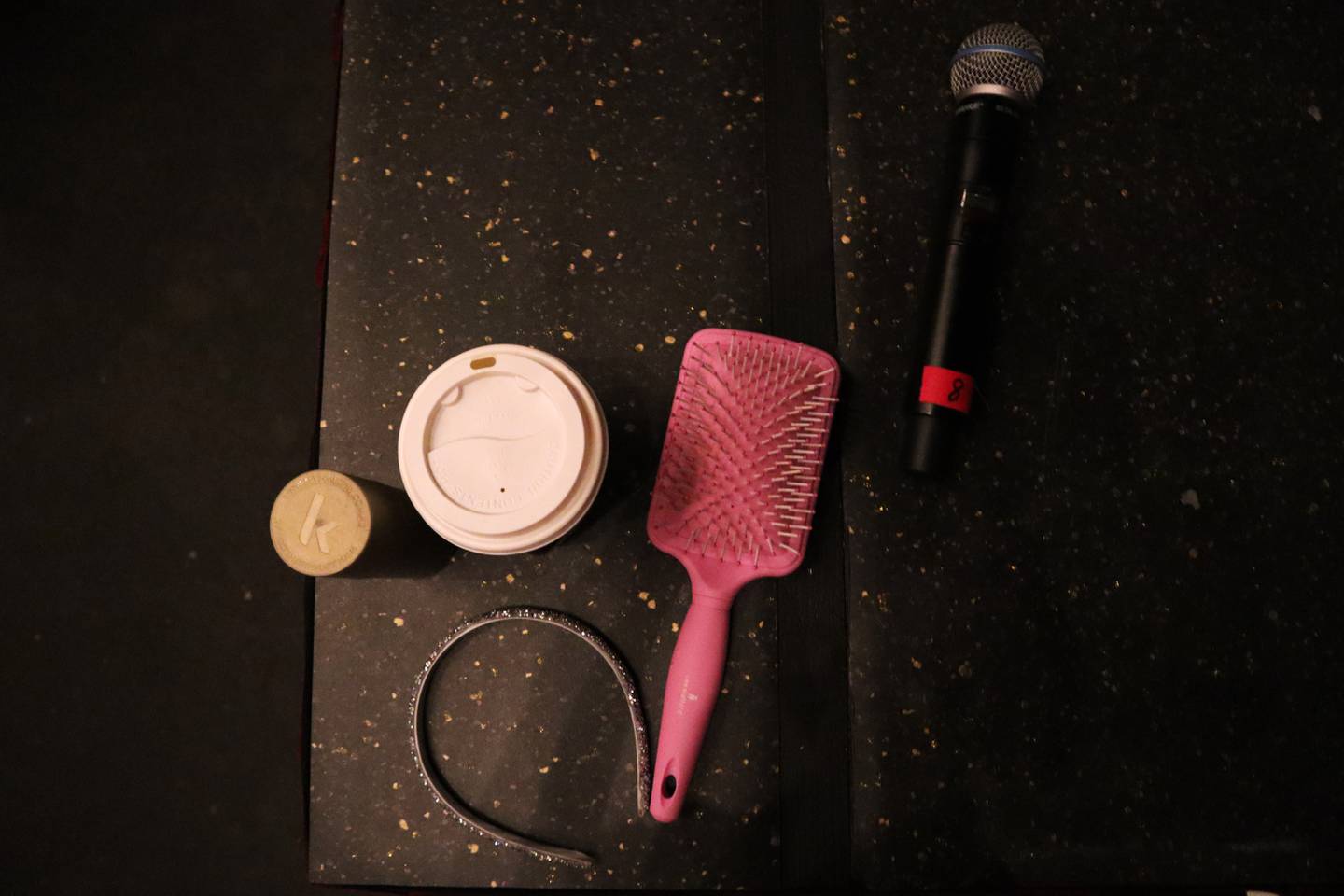 Et hårbånd, en mikrofon, en rosa hårbørste og en kaffekopp.
