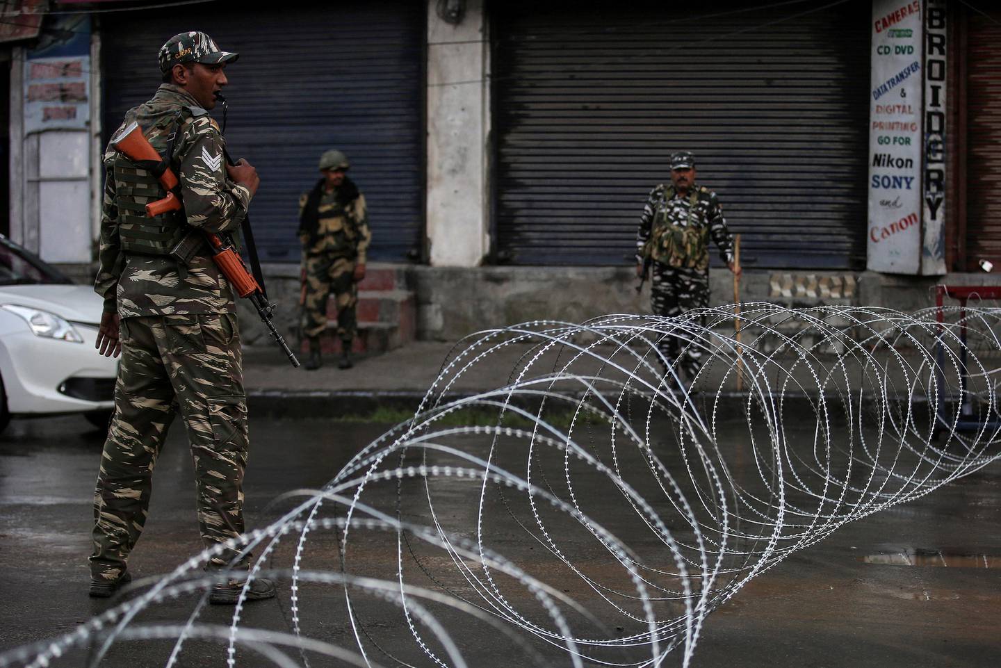 Indian security forces personnel stand guard next to concertina wire laid across a road during restrictions after the government scrapped special status for Kashmir, in Srinagar August 7, 2019. REUTERS/Danish Ismail