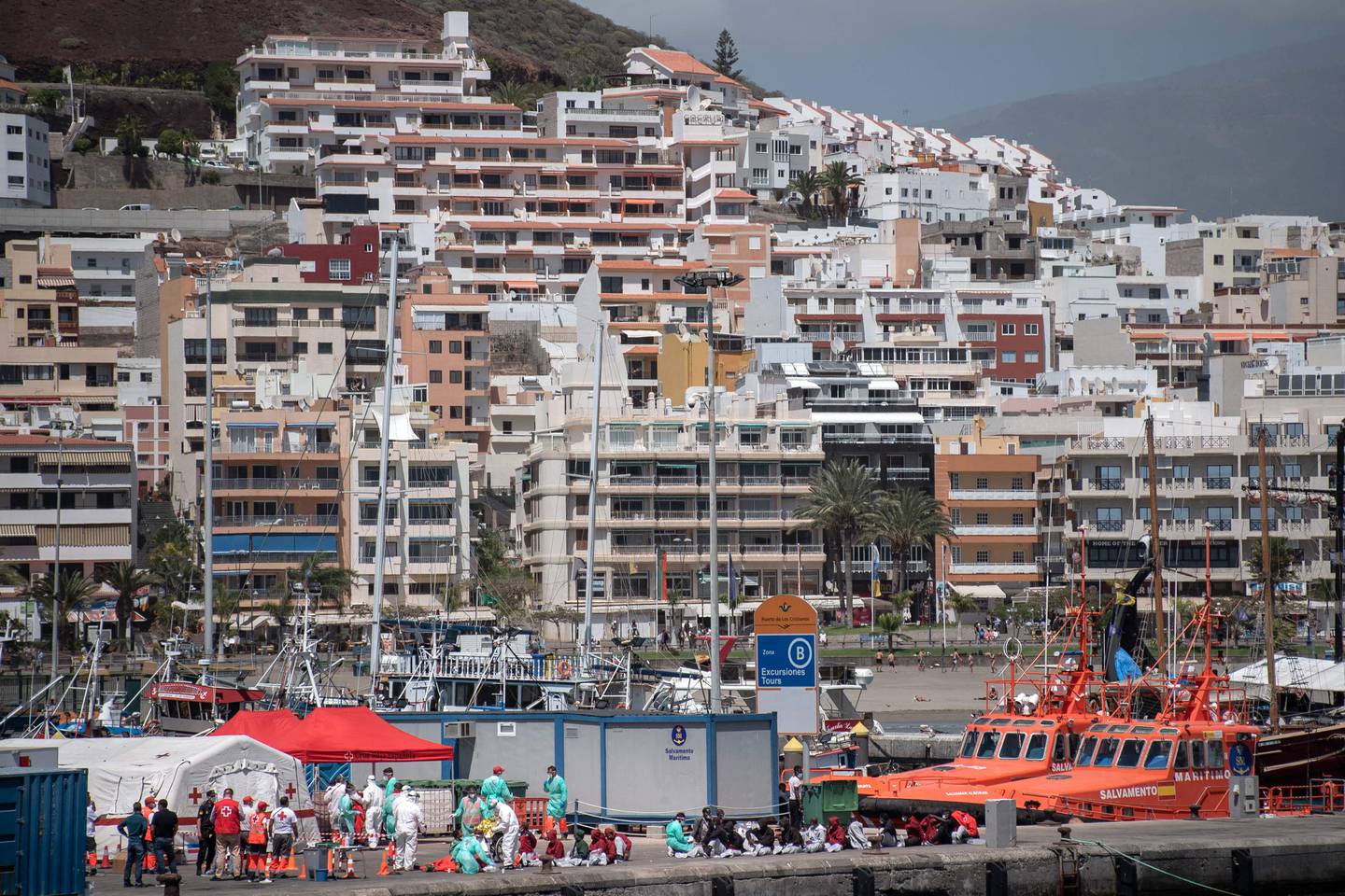 Migranter sitter på kaia i byen Los Cristianos på øya Tenerife etter å ha blitt reddet på havet i 2021.