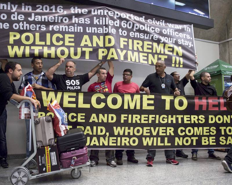 «Velkommen»: Politi og brannmenn tok imot nyankomne på flyplassen i Rio med disse plakatene i starten av juli. De streiket og protesterte mot at lønnsutbetalingene deres fra myndighetene lar vente på seg. 