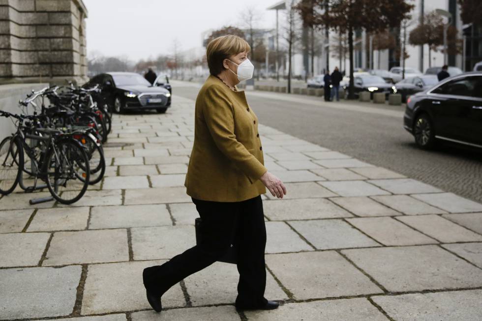 Tysklands kansler Angela Merkel med munnbind forlater parlamentsbygningen i Berlin.