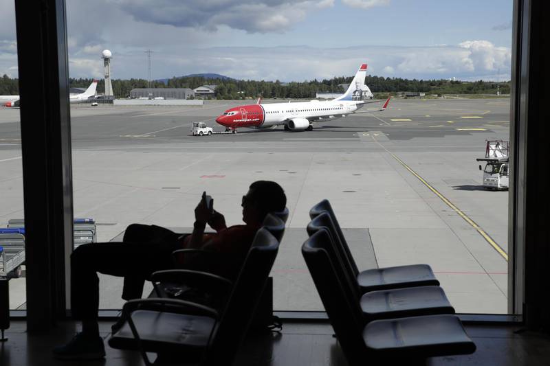 Gardermoen 20200709. 
Et fly fra Norwegian og en passasjer med mobiltelefon på Oslo lufthavn. 
Foto: Vidar Ruud / NTB