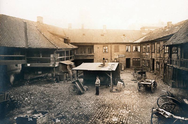 Brusteinsbelagt bakgård med vogner og kjerrer i Brugata 7 på Vaterland, en av byens travle gater med trafikk  inn og ut av byen og en rekke verksteder og skjenkesteder i 1889.