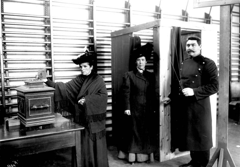 HISTORISK ØYEBLIKK: To kvinner og en vakt grepet av stundens alvor ved stortingsvalget i Drammen i 1909.FOTO: ANDERS B. WILSE/ NORSK FOLKEMUSEUM