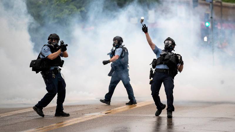 A police officer throws a tear gas canister towards protesters at the Minneapolis 3rd Police Precinct, following a rally for George Floyd on Tuesday, May 26, 2020, in Minneapolis. Four Minneapolis officers involved in the arrest of Floyd, a black man who died in police custody, were fired Tuesday, hours after a bystander's video showed an officer kneeling on the handcuffed mans neck, even after he pleaded that he could not breathe and stopped moving. (Richard Tsong-Taatarii/Star Tribune via AP)