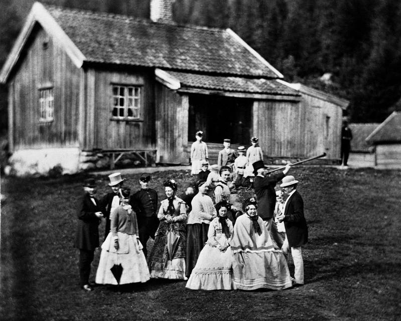 AKERSHUSSTIL: Thomas Heftye likte å la seg fotografere med gjester foran den gamle husmannsstua som antakelig var fra 1700-tallet og i bruk til omkring 1897. 