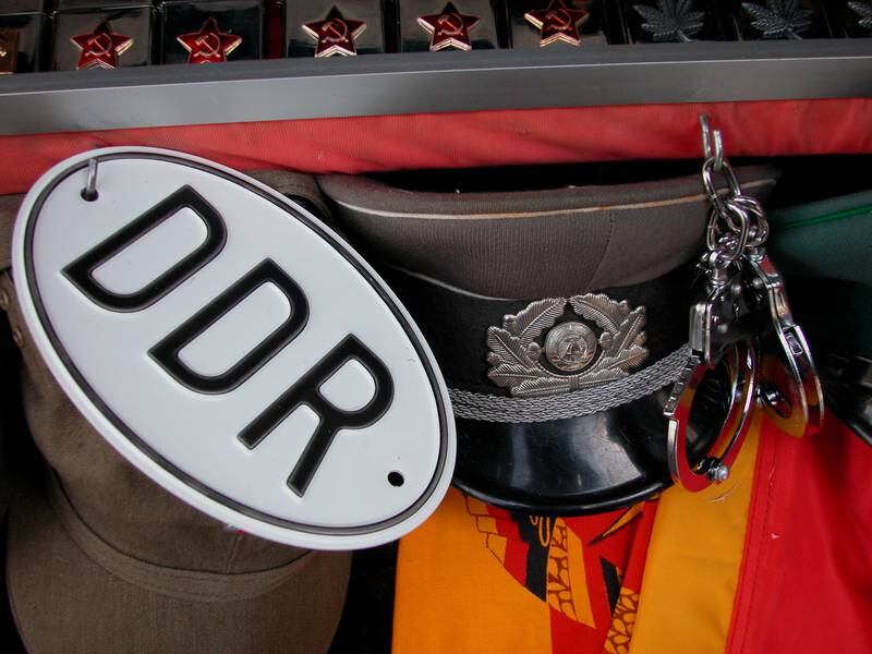 Salgsbod med gamle DDR effekter, bilskilt, flagg, uniformsluer, håndjern, pins formet som stjerner med hammer og sigd.