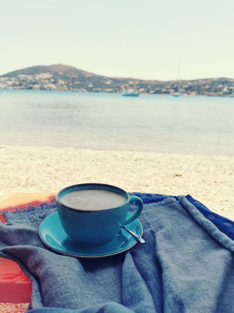 Kaffekopp på pledd ved en strand.
