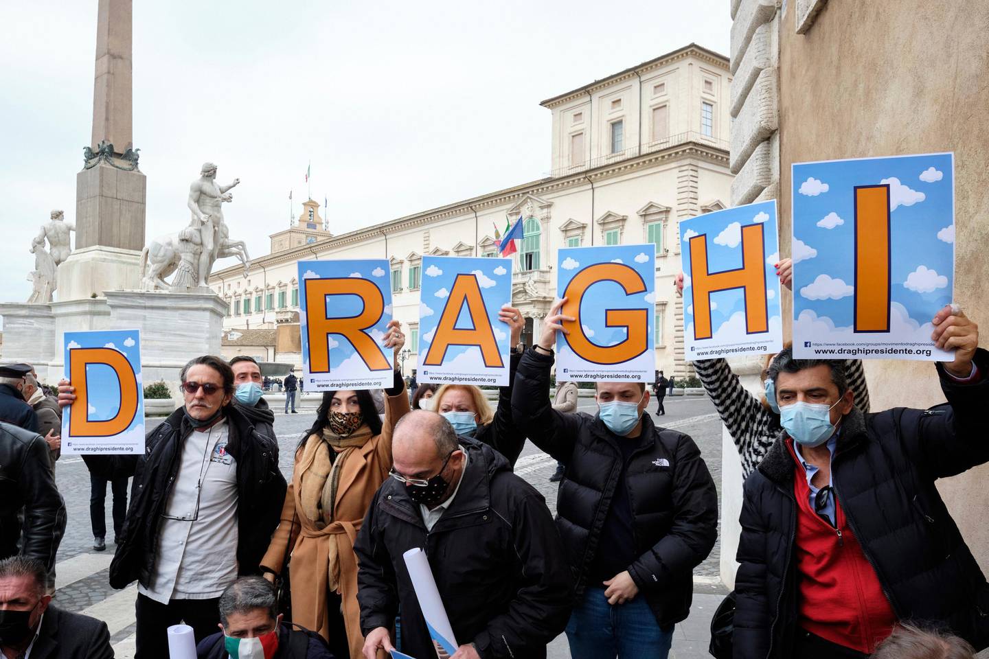 A group of supporters hold placards reading "Draghi President" in front of the Quirinale Presidential palace in Rome Wednesday, Feb. 3, 2021. Former European Central Bank President Mario Draghi arrived for talks with Italian President Sergio Mattarella to discuss a mandate to form a new government. (Mauro Scrobogna/LaPresse via AP)