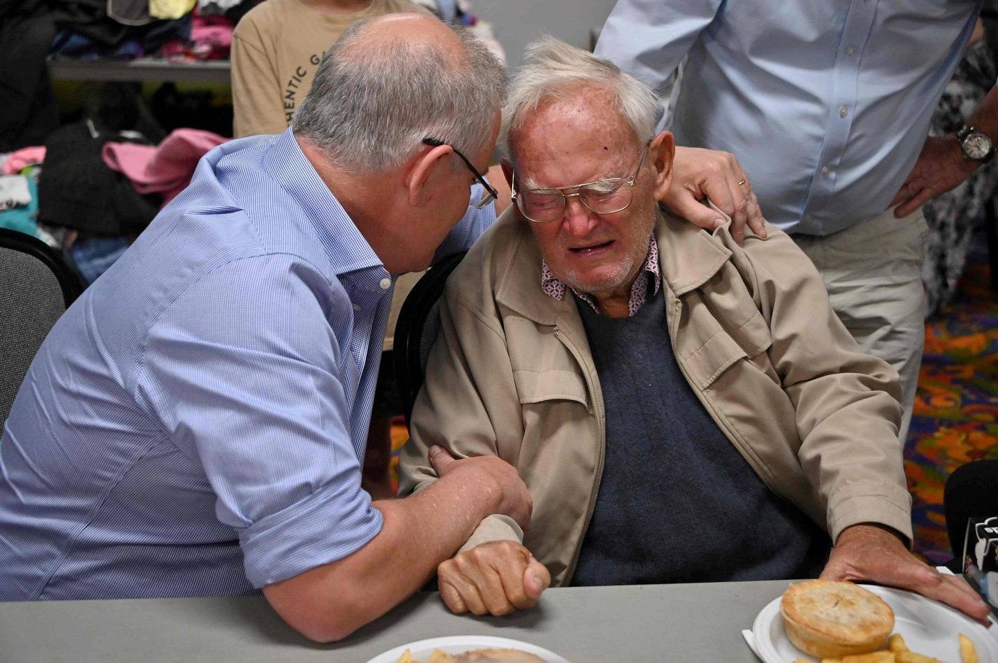 Australias statsminister Scott Morrison trøster 85 år gamle Owen Whalan, som måtte evakuere hjemmet sitt for noen dager siden. Foto: NTB scanpix