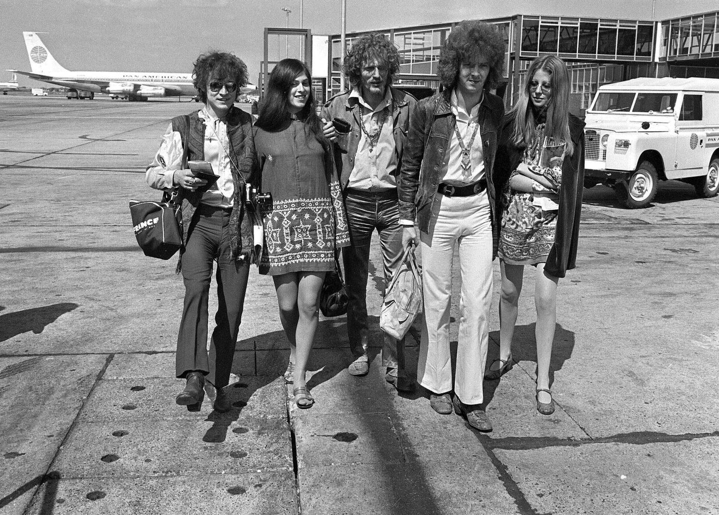 Eric Clapton (i hvite bukser) og Cream med uidentifisert følge på Heathrow i 1967: gitarist Jack Bruce, trommis Ginger Baker og gitarist Eric Clapton. Foto: AP Photo/NTB Scanpix