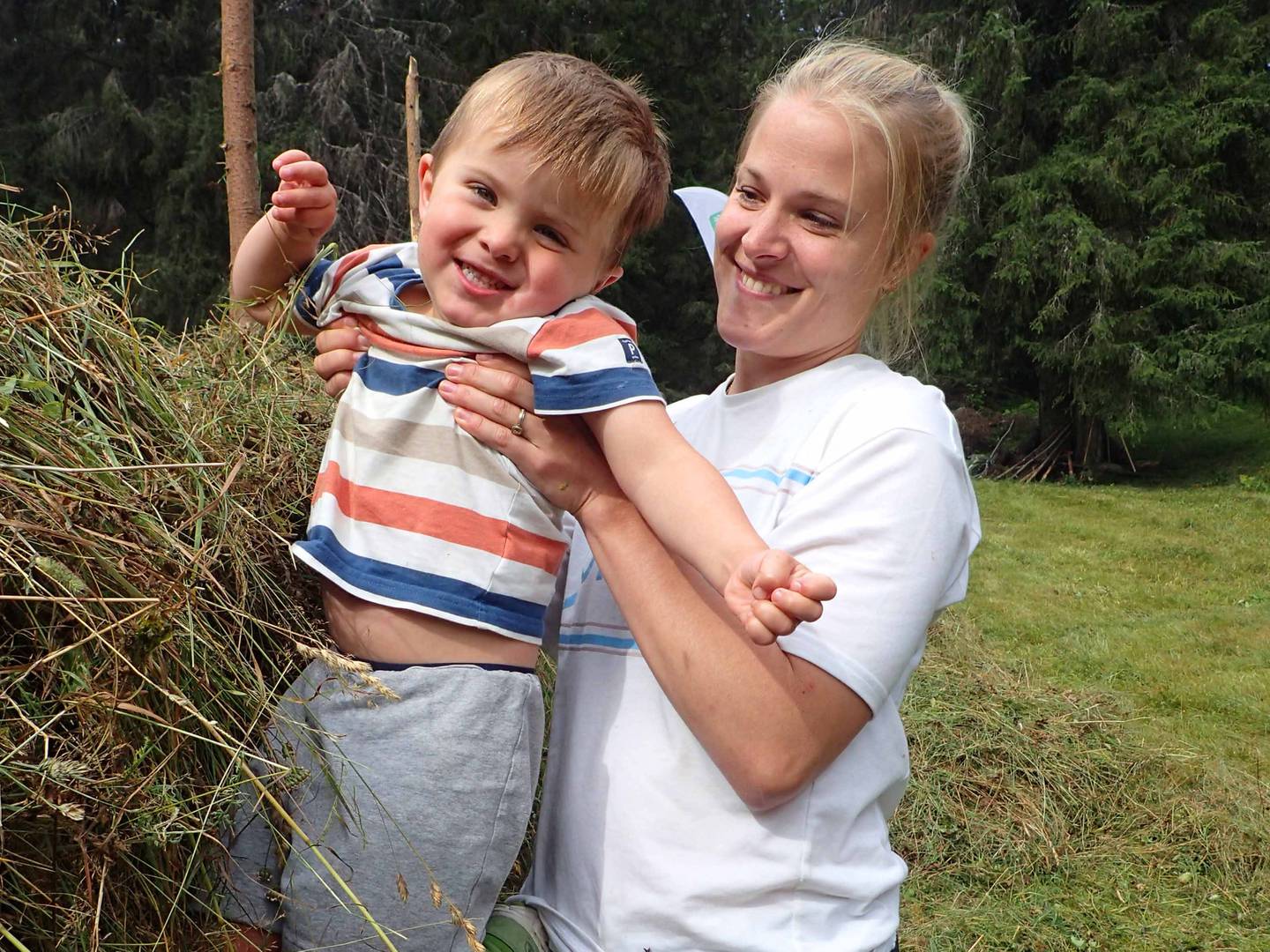 Skogforvalter Malin Sørensen fra Drammen kommune hadde med sønnen, Emil (3. Treåringen måtte ha litt hjelp av mamma for å få lagt gress på toppen av hesjene på Myresetervollen.