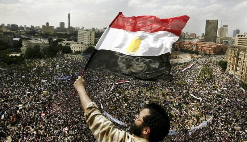 2011: En mann veiver med det egyptiske flagget over Tahrir-plassen i Kairo i april 2011, to måneder etter at opptøyene  mot diktatoren Hosni Mubarak startet. FOTO: MISAM SALEH/NTB SCANPIX