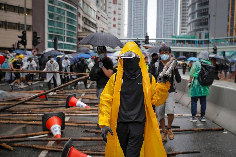 Demonstrators carry in bamboos sticks to block a road during a protest in Hong Kong, Sunday, Aug. 25, 2019. Umbrella-carrying protesters took to the streets in the rain Sunday in Hong Kong's latest pro-democracy demonstration, one day after the return of clashes with police who used tear gas to disperse them. (AP Photo/Kin Cheung)