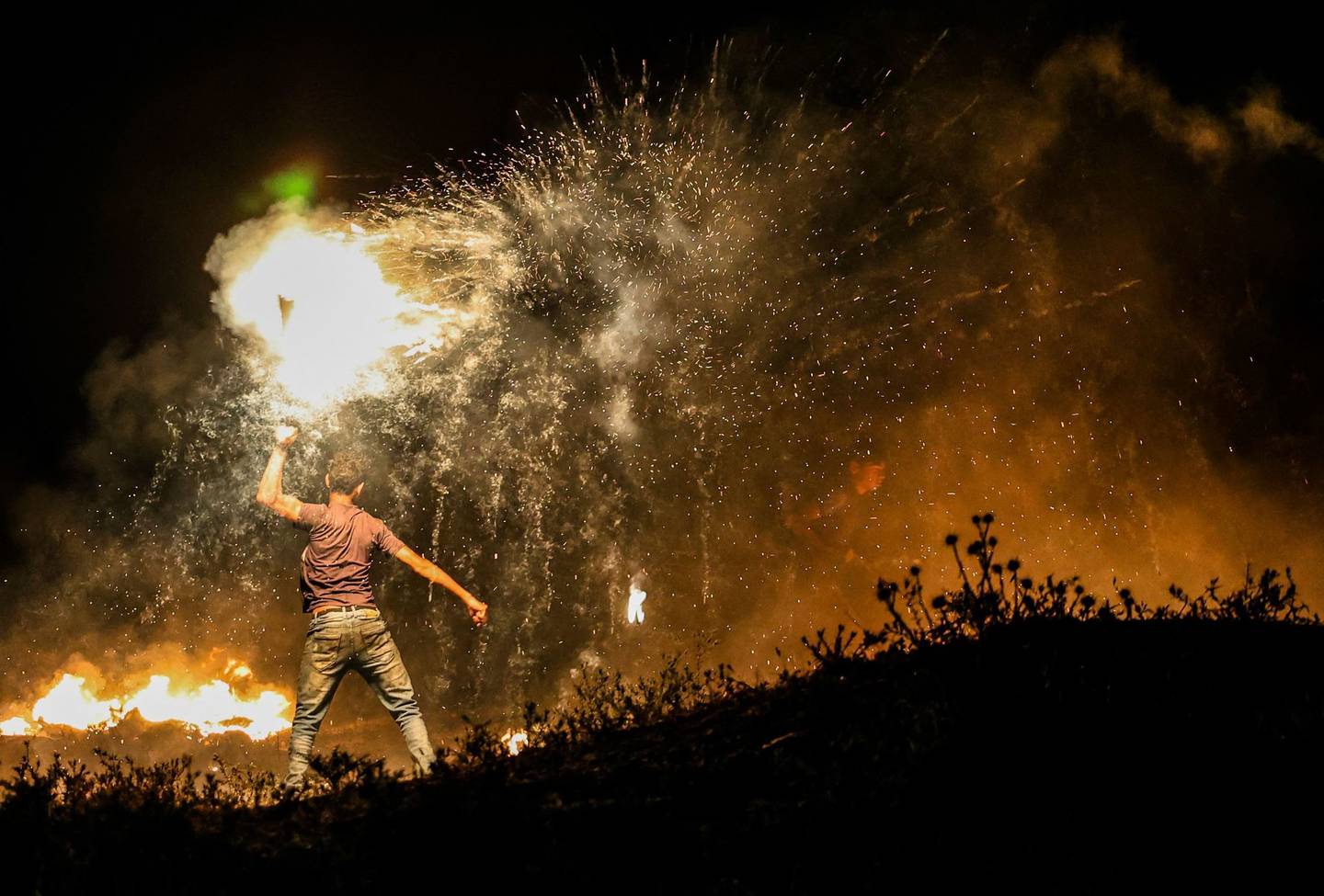 A Palestinian protester throws a burning projectile towards Israeli forces during a demonstration east of Gaza City by the border with Israel, on June 15, 2021, to protest the Israeli ultranationalist March of the Flags in Jerusalem's Old City which celebrates the anniversary of Israel's 1967 occupation of Jerusalem's eastern sector. (Photo by MAHMUD HAMS / AFP)