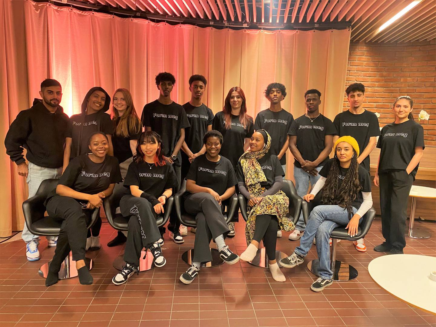 15 ungdommer samlet, med svarte t-skjorter med påskriften "Foran meg"